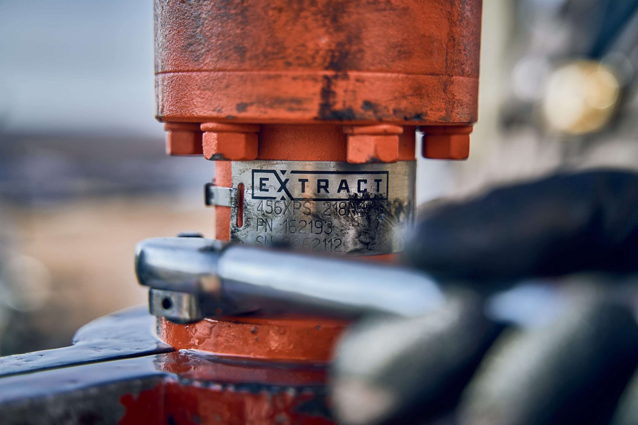 in Midland, Tx, a Gloved Hand Tightens a Bolt on an Orange “extract” Valve, Showing Industrial Precision Up Close. Commercial Photography – Amatucci Photography - Amatucci Photography In midland tx a gloved hand tightens a bolt on an orange extract valve showing industrial precision up close Commercial photography amatucci photography