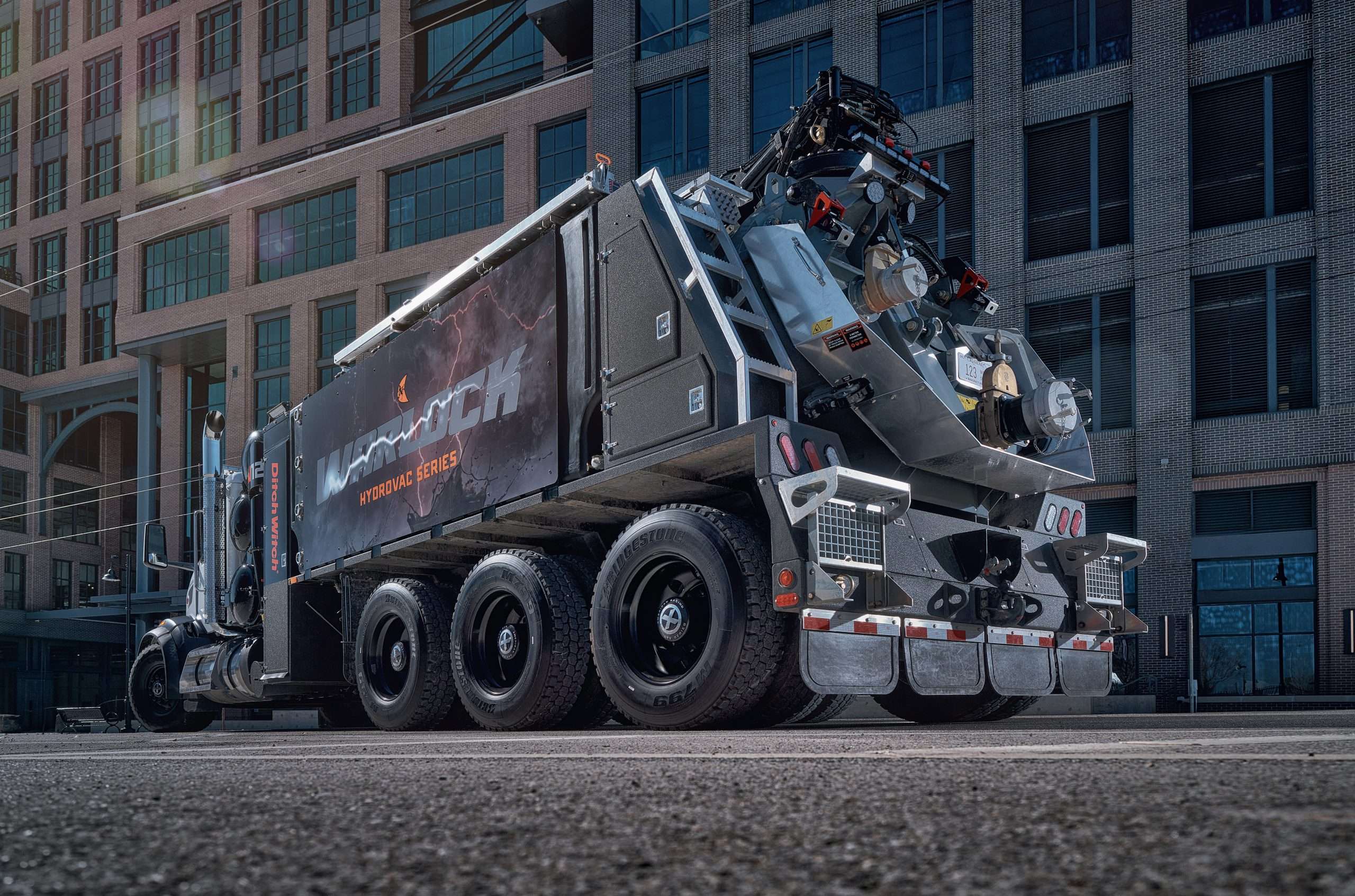a Sleek Black Utility Truck Labeled "mammoth" is Parked by a Modern Brick Building, Six Wheels and Equipment Visible. Commercial Photography – Amatucci Photography - Amatucci Photography A sleek black utility truck labeled ditch witch warlock w is parked by a modern brick building six wheels and equipment visible Commercial photography amatucci photography