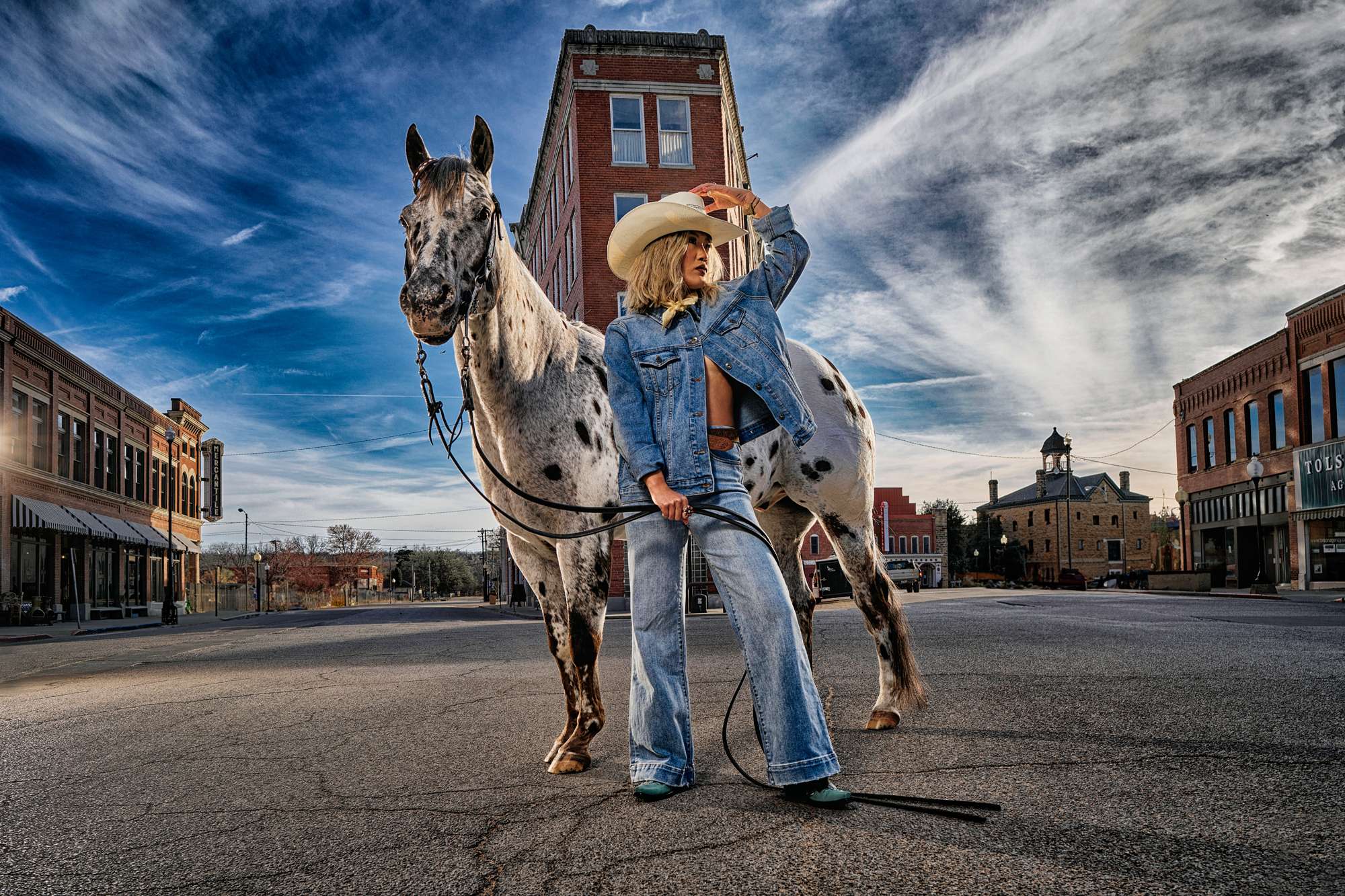Western Hotel Shot in Pawhuska with a Horse and Model - Amatucci Photography Female in a cowboy hat jeans and jacket standing confidently in front of a horse at frontier hotel in pawhuska capturing a bold western inspired aesthetic