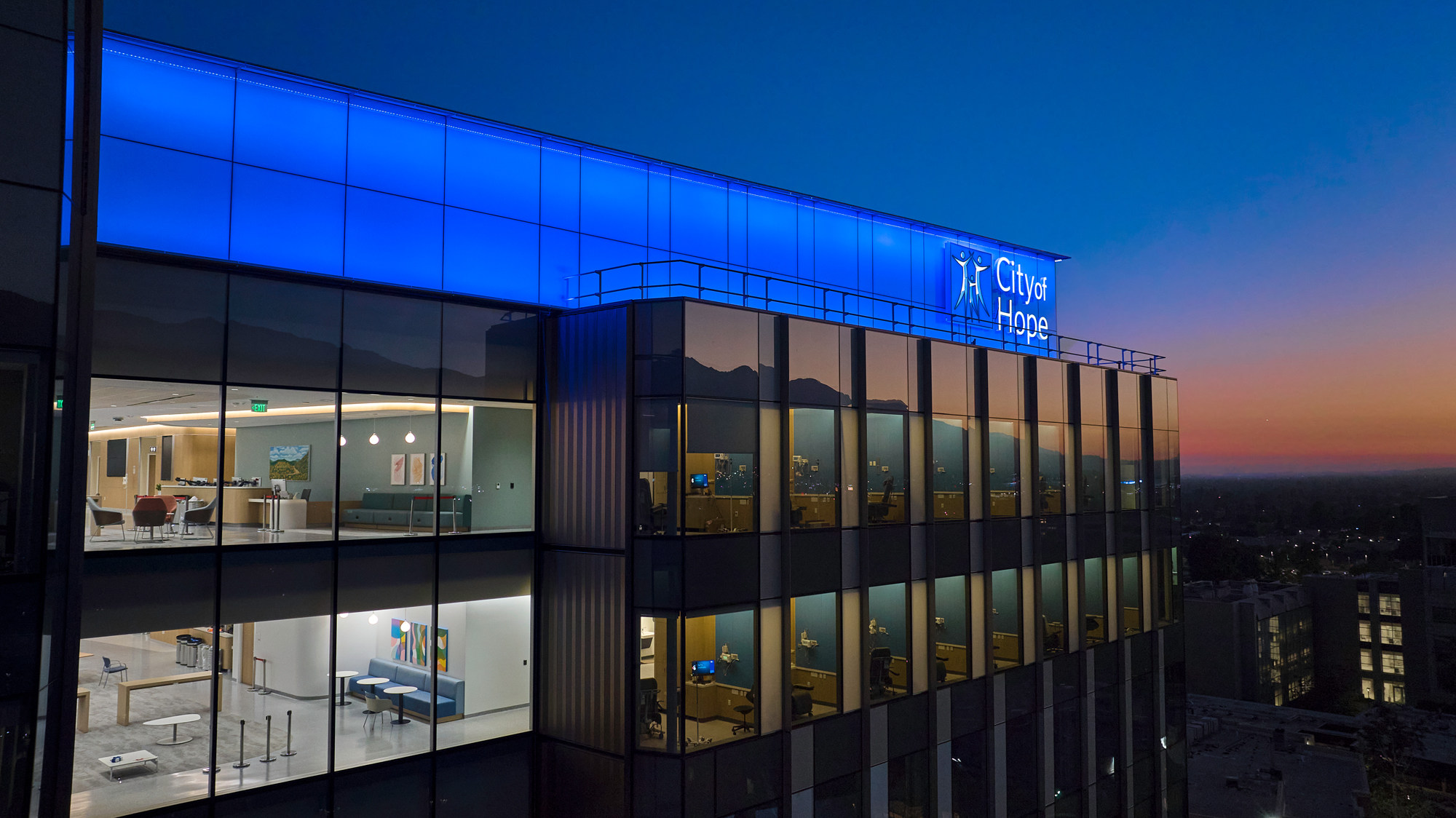 City of Hope Hospital at Dusk, Glass Building Glowing with Blue-white Logo, Warm Lights and City Skyline in the Background. – Amatucci Photography - Amatucci Photography City of hope hospital at dusk glass building glowing with blue white logo warm lights and city skyline in the background amatucci photography
