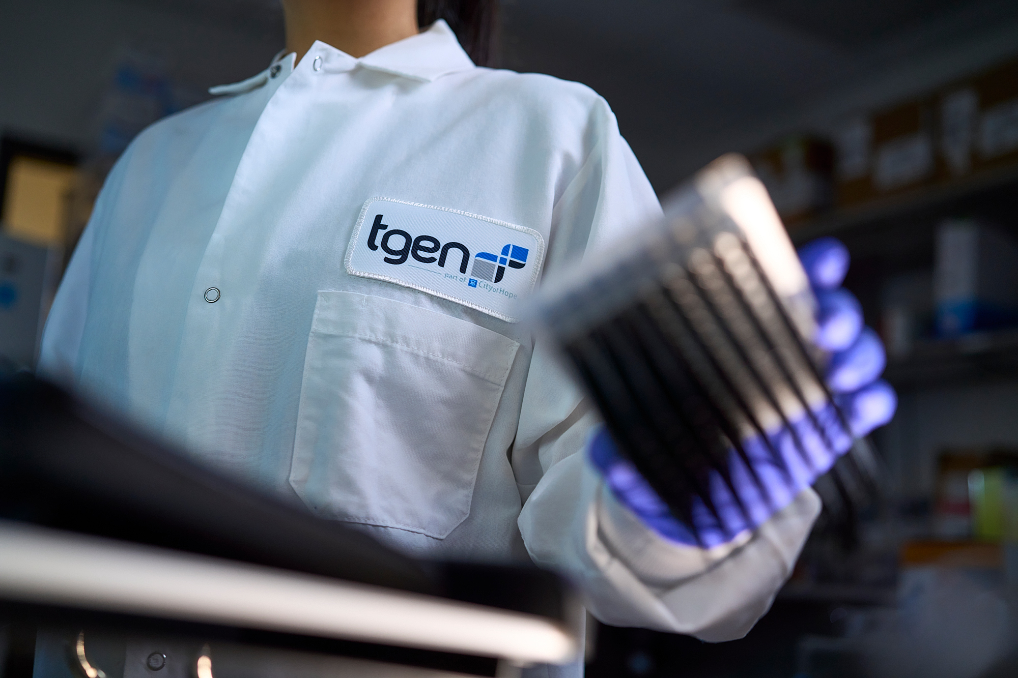 in a Phoenix Lab, a Scientist in a Tgen Coat and Blue Gloves Holds Test Tubes at a Biotech Conference, Focus on Logo and Samples. – Amatucci Photography - Amatucci Photography In a phoenix lab a scientist in a tgen coat and blue gloves holds test tubes at a biotech conference focus on logo and samples amatucci photography