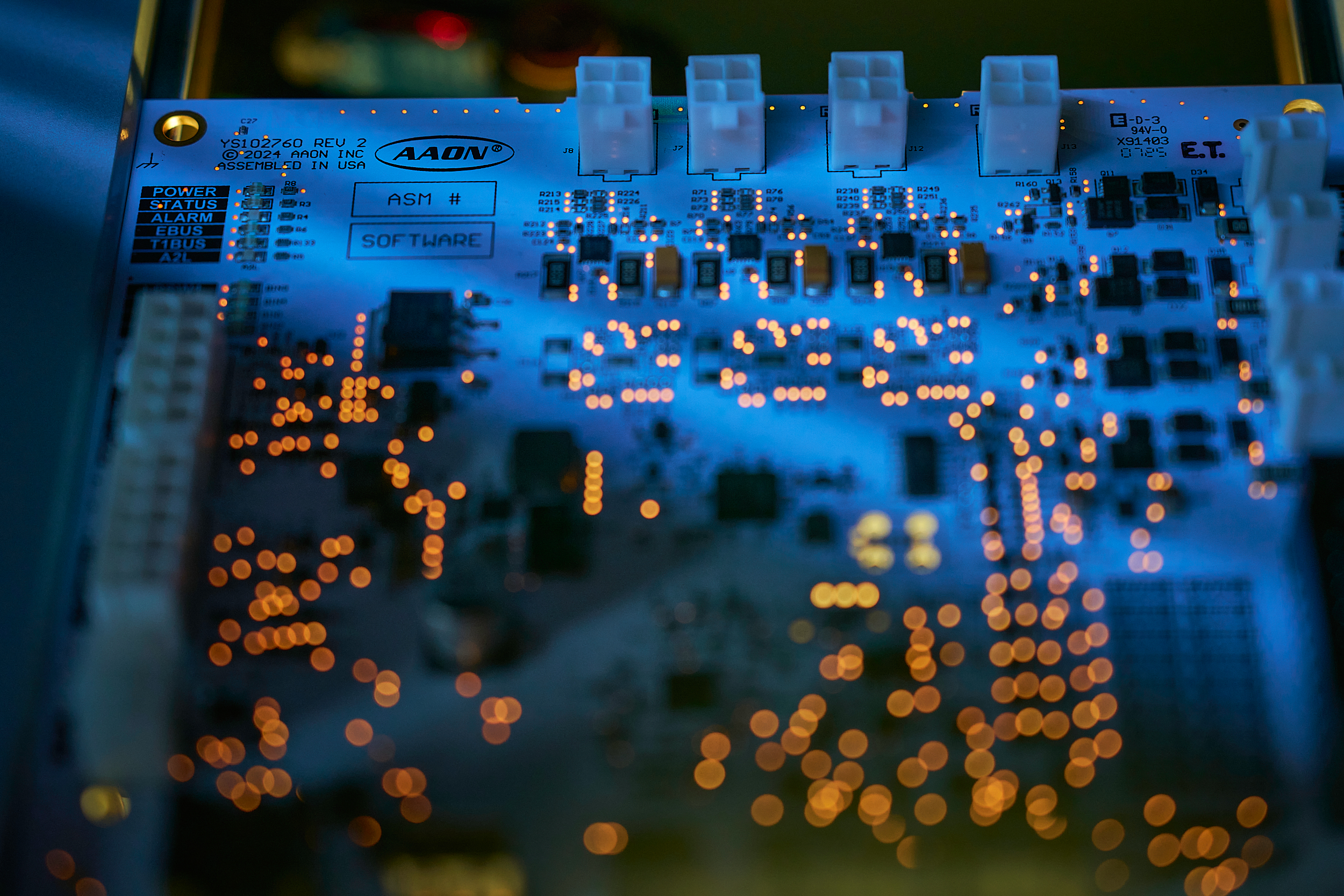 Close-up of a Lit Circuit Board with Blue Glow, Orange Leds, and Labels Like Software at a Tech Expo Booth, Connectors at Top. – Amatucci Photography - Amatucci Photography Close up of a lit circuit board with blue glow orange leds and labels like software at a tech expo booth connectors at top amatucci photography