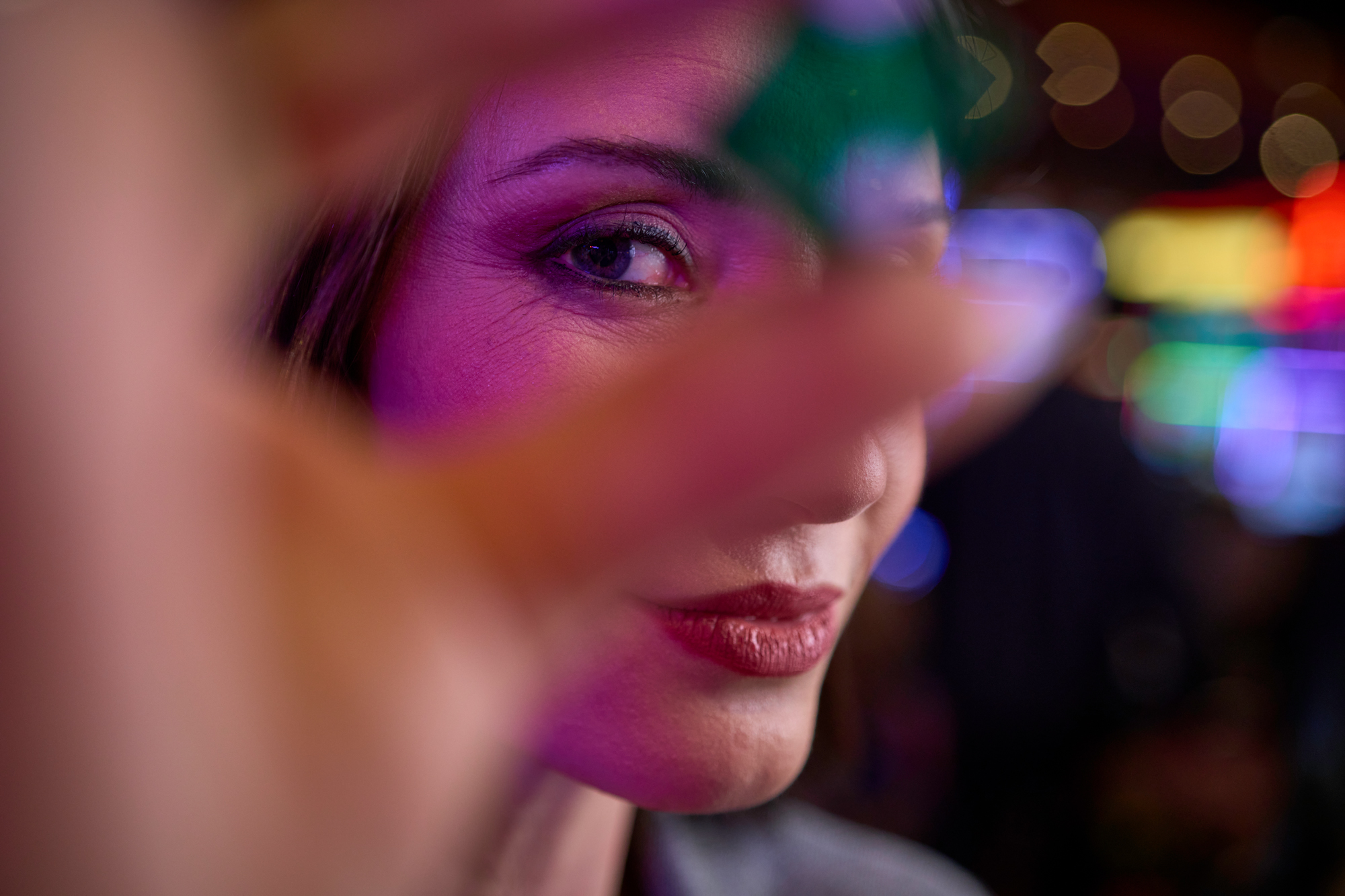 a Woman with Vivid Makeup Peers Through a Green Casino Chip; Her Eye is Sharp Amid Lively Vegas Casino Lights at Night. – Amatucci Photography - Amatucci Photography A woman with vivid makeup peers through a green casino chip her eye is sharp amid lively vegas casino lights at night amatucci photography